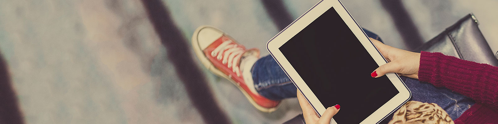 hero_admissions_tablet-red-shoes_1600x400.jpg student with tablet and red sneakers
