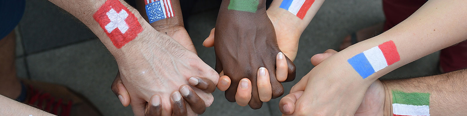 hands held in center ring with international flags painted on wrists