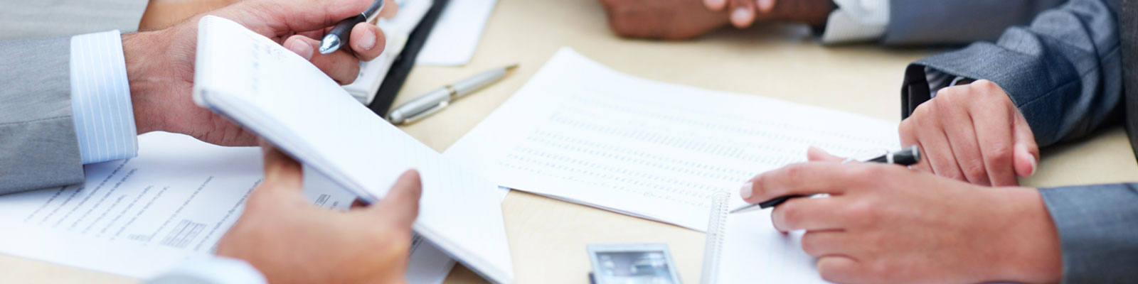 tabletop view of people writing with pens and paper