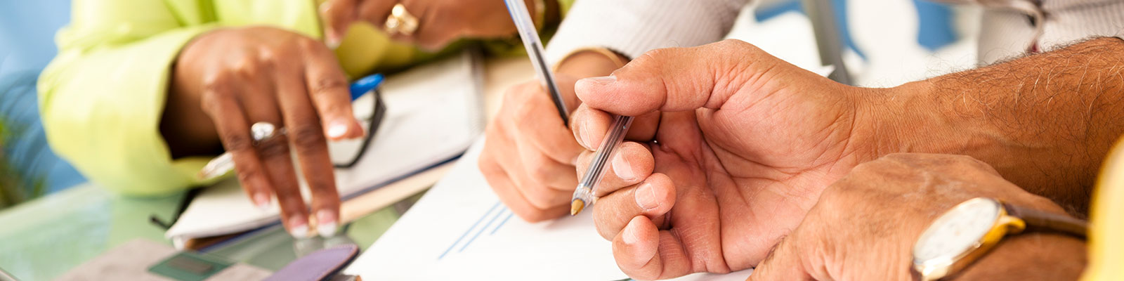 tabletop view of people writing with pens