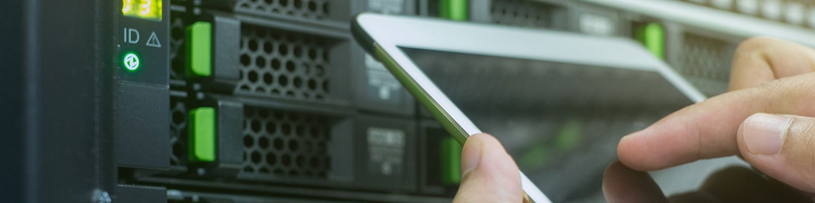 person making notes on mobile tablet in front of network servers