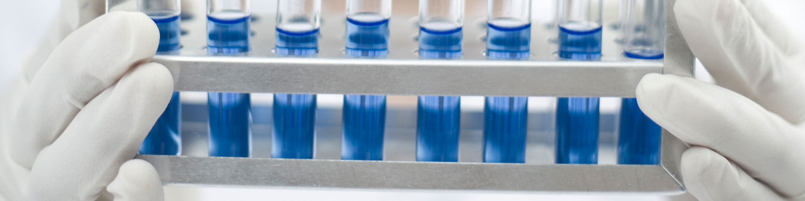 test tubes of blue liquid held by gloved hands