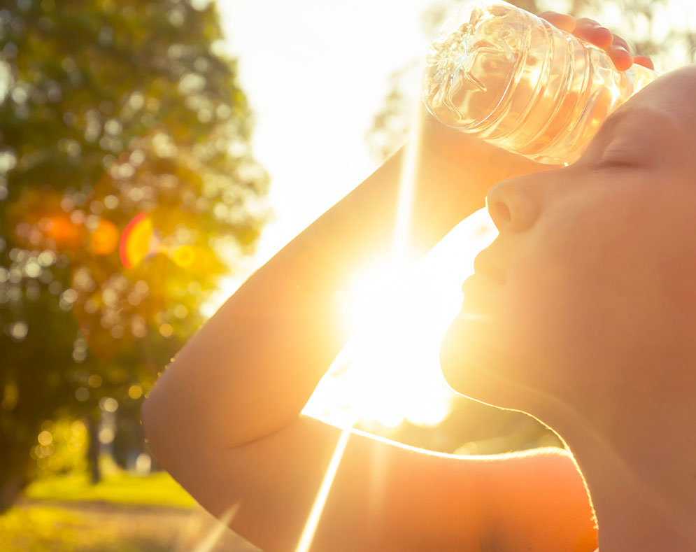 Woman holding a water bottle to her head in the summer heat