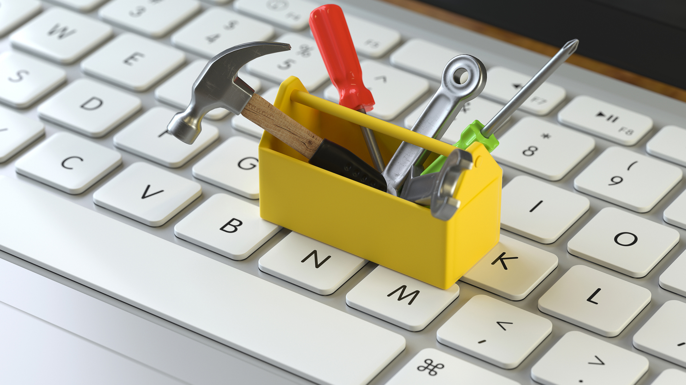 White keyboard with yellow toolbox and tools placed on top