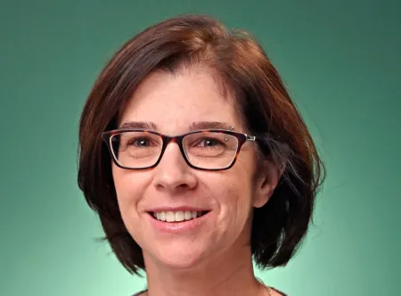Dr. MaryBeth Chrostowsky wearing a flowery blouse and black site glasses smiling at camera