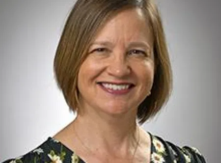 Dr. Christine Miller Divine wearing a black blouse with color flowers and smiling at the camera