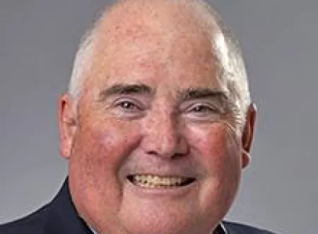 Dr. Michael Gagnon wearing a blue striped shirt and blue jacket smiling at camera