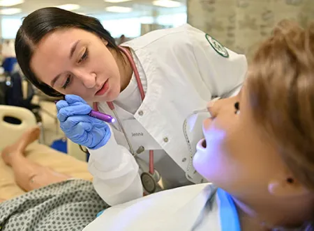 GGC nursing student examining simulation lab manikin