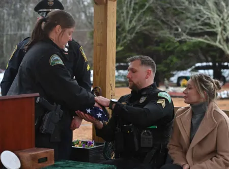 Captain Rebecca Lawler presents Sgt. Chris Wragg the American flag during Officer Buddy's funeral at the Pet Angel Memorial Center in Bethlehem, GA.