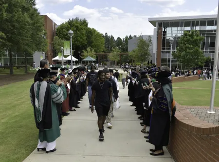 First-year students walk between two lines of welcoming faculty