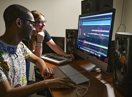 Two students editing audio on a computer
