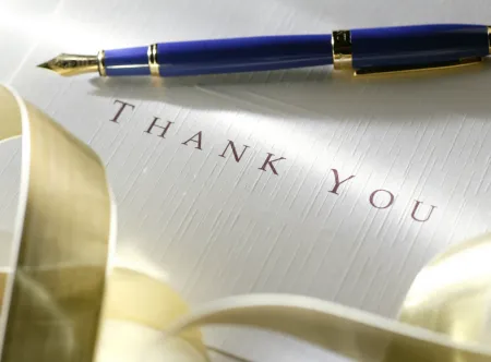 Thank you card, gold ribbon, and blue and gold fountain pen 