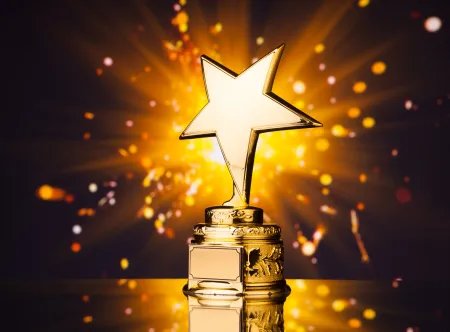 Getty image of a gold star trophy and gold sparks in background