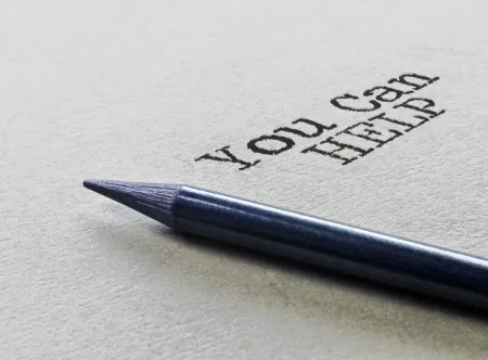 The words You Can Help written on a sheet of card stock with pen displayed 