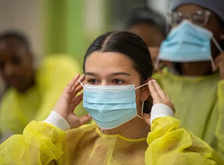 Jonesboro High School student Abril Flores Alvarez puts on PPE, Personal Protective equipment, while in the GGC skill labs