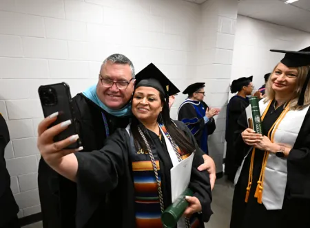 Dr. Matthew Bogan, (left) professor of special education and special education and social foundations chair in the School of Education, poses with the school’s graduates during the May 2025 commencement ceremony. 
