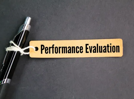 Image of a tag reading "Performance Evaluation" attached to a pen with white string 