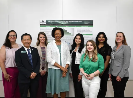 Dr. Jann L. Joseph and Dean Tyler Yu with faculty and staff standing in front of a poster at CREATES 2025
