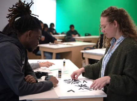 A professor reviews a student's two-dimensional art work