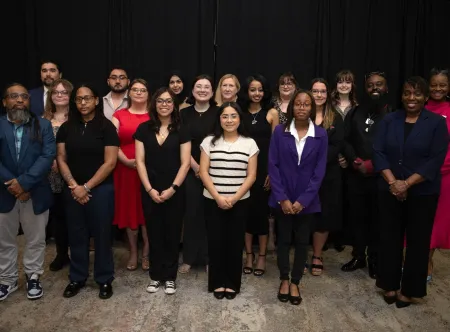 A group photo of 19 people dressed in business attire and posing for the picture