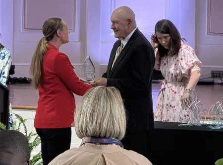 Dr. Marieke Schilpzand receives award from USG Chancellor Sonny Perdue at the Executive Leadership Institute Celebration Luncheone 