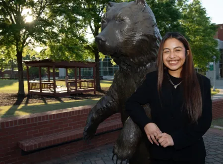 GGC Junior Zoreida Reyes-Garcia posing next to a bear statue on campus.