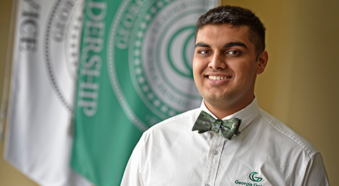 GGC student posing in front of Four Pillar flags