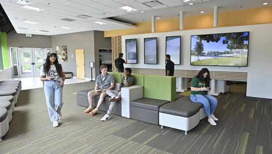 Students seated talking and exploring the digital signs in the Grizzly Welcome Center
