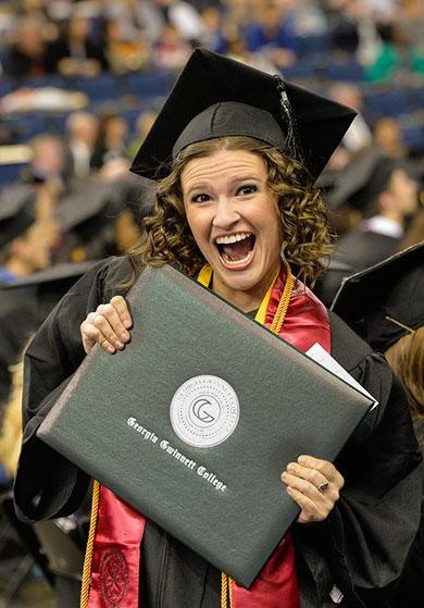 Female student displaying diploma at commencement