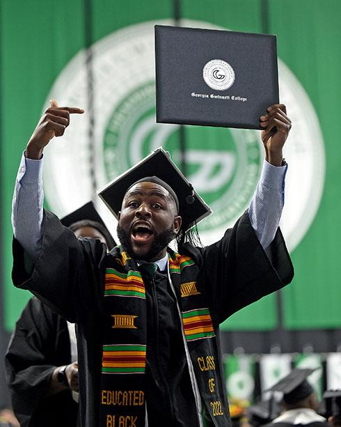 Graduate holding up diploma at commencement
