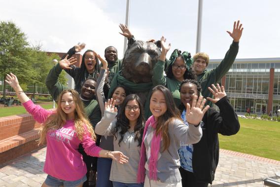GGC students waving and surrounding Grizzly statue