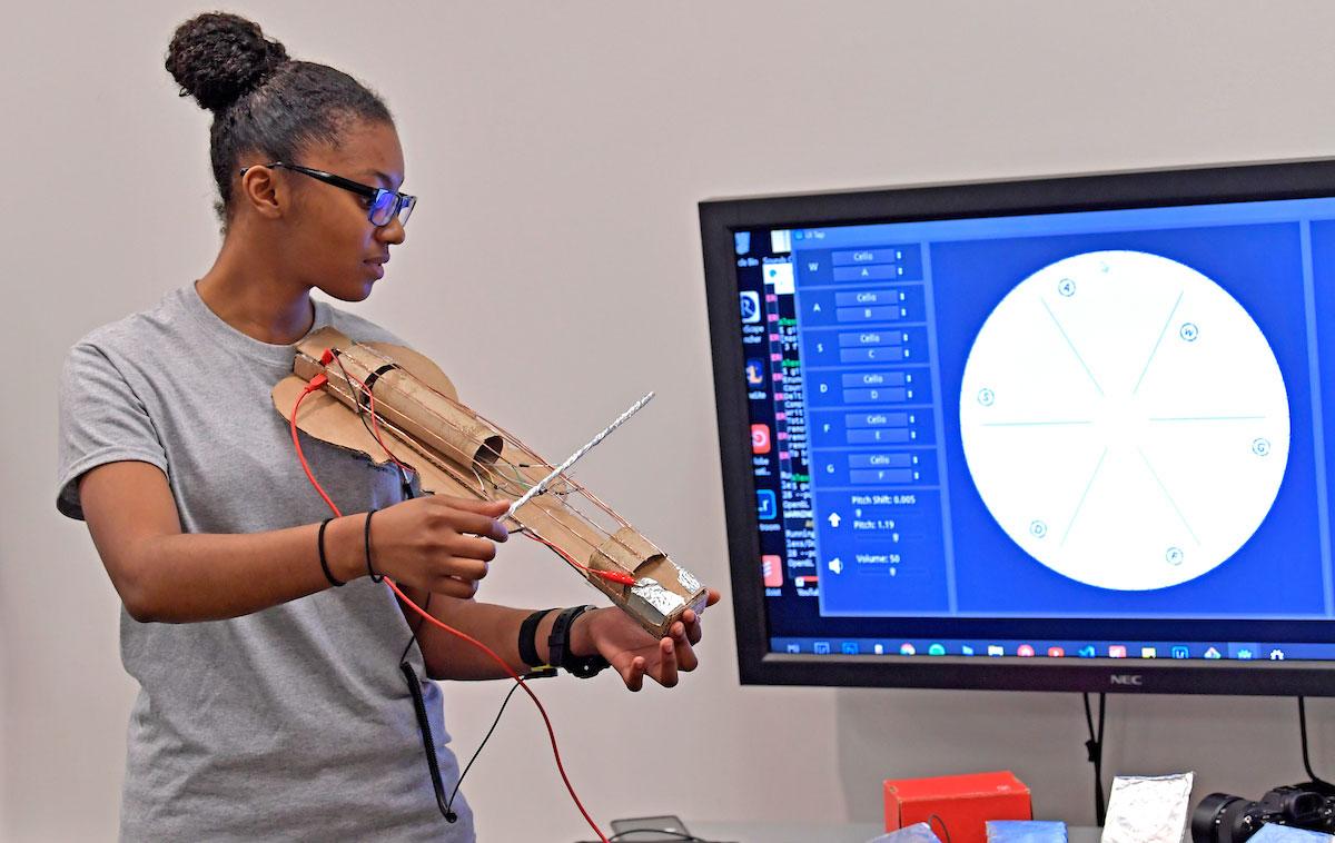 Information technology student playing experimental string instrument
