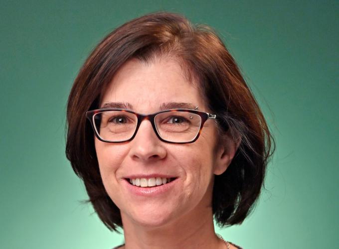 Dr. MaryBeth Chrostowsky wearing a flowery blouse and black site glasses smiling at camera