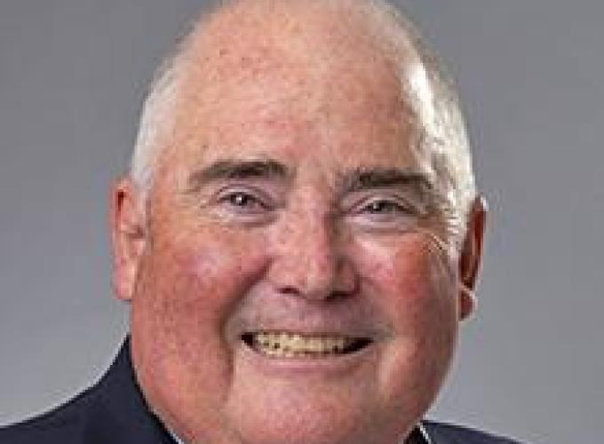 Dr. Michael Gagnon wearing a blue striped shirt and blue jacket smiling at camera