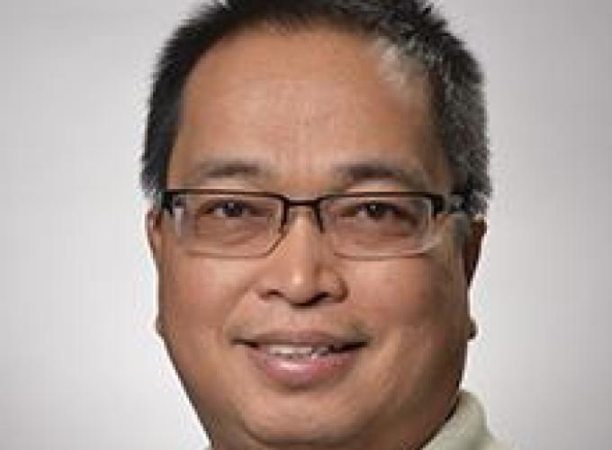 Dr. Melchor C. de Guzman smiling at camera