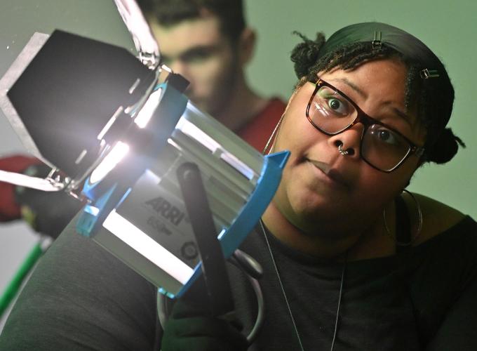 Student setting up a film light