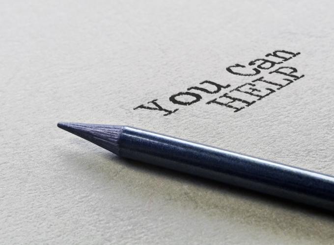 The words You Can Help written on a sheet of card stock with pen displayed 