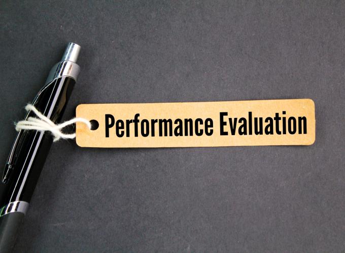 Image of a tag reading "Performance Evaluation" attached to a pen with white string 