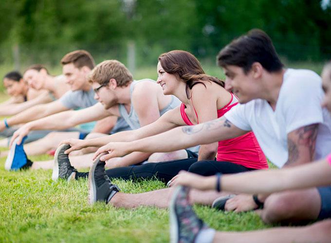 Students stretching while seated on the grass