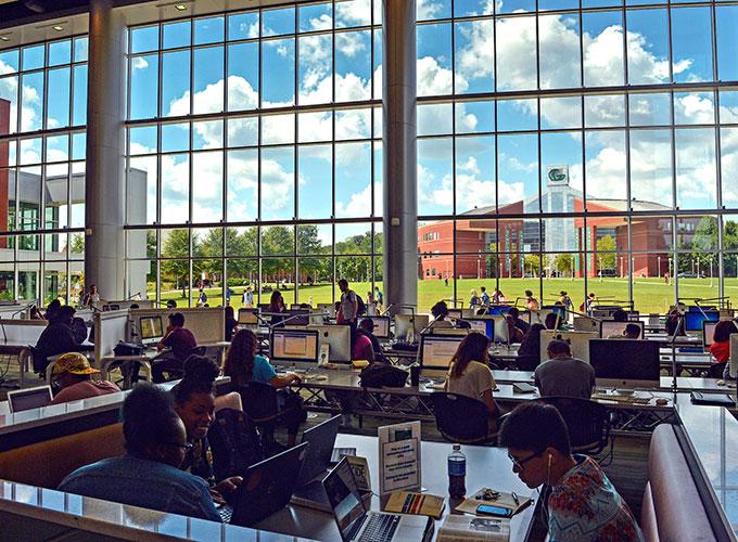 GGC students studying in the library with GGC's signature building pictured in the background through the window