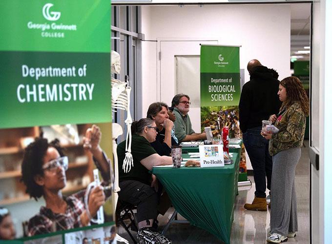 Event participants stop at the Biological Sciences table to ask professors questions about the major