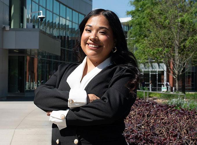 GGC graduate Gaby Sifuentes posing in front of the library