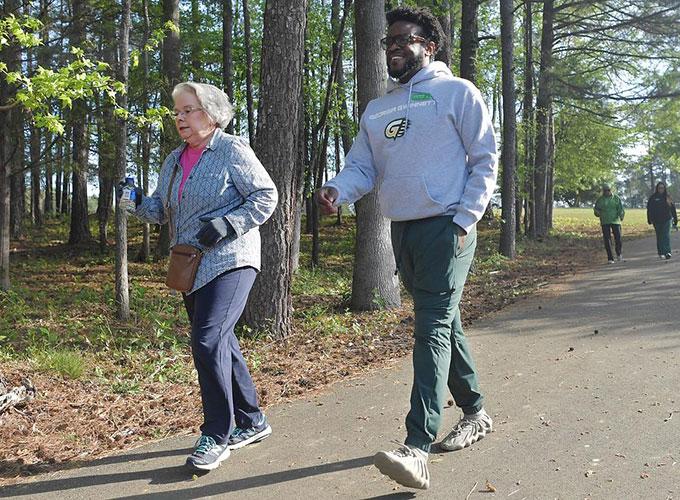 Judy Wilson and GGC exercise science student Simeon Brooks make their way around the lake as part of the "Walk It Out Wednesday" program at the Bethesda Park Senior Center