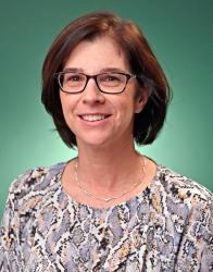 Dr. MaryBeth Chrostowsky wearing a flowery blouse and black site glasses smiling at camera