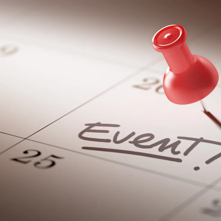 monthly paper calendar with thumbtack pinned to a date marking an event