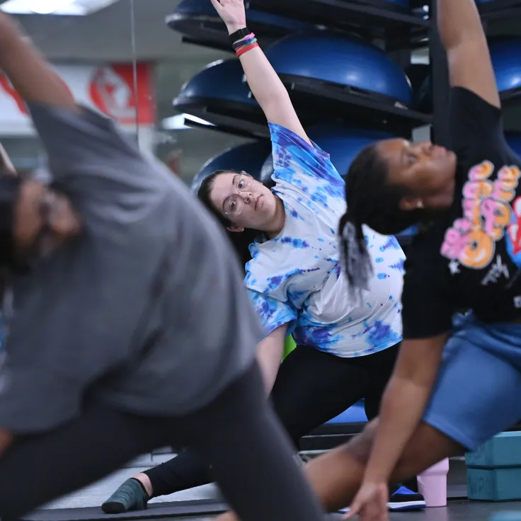 Three female students stretching during yoga class