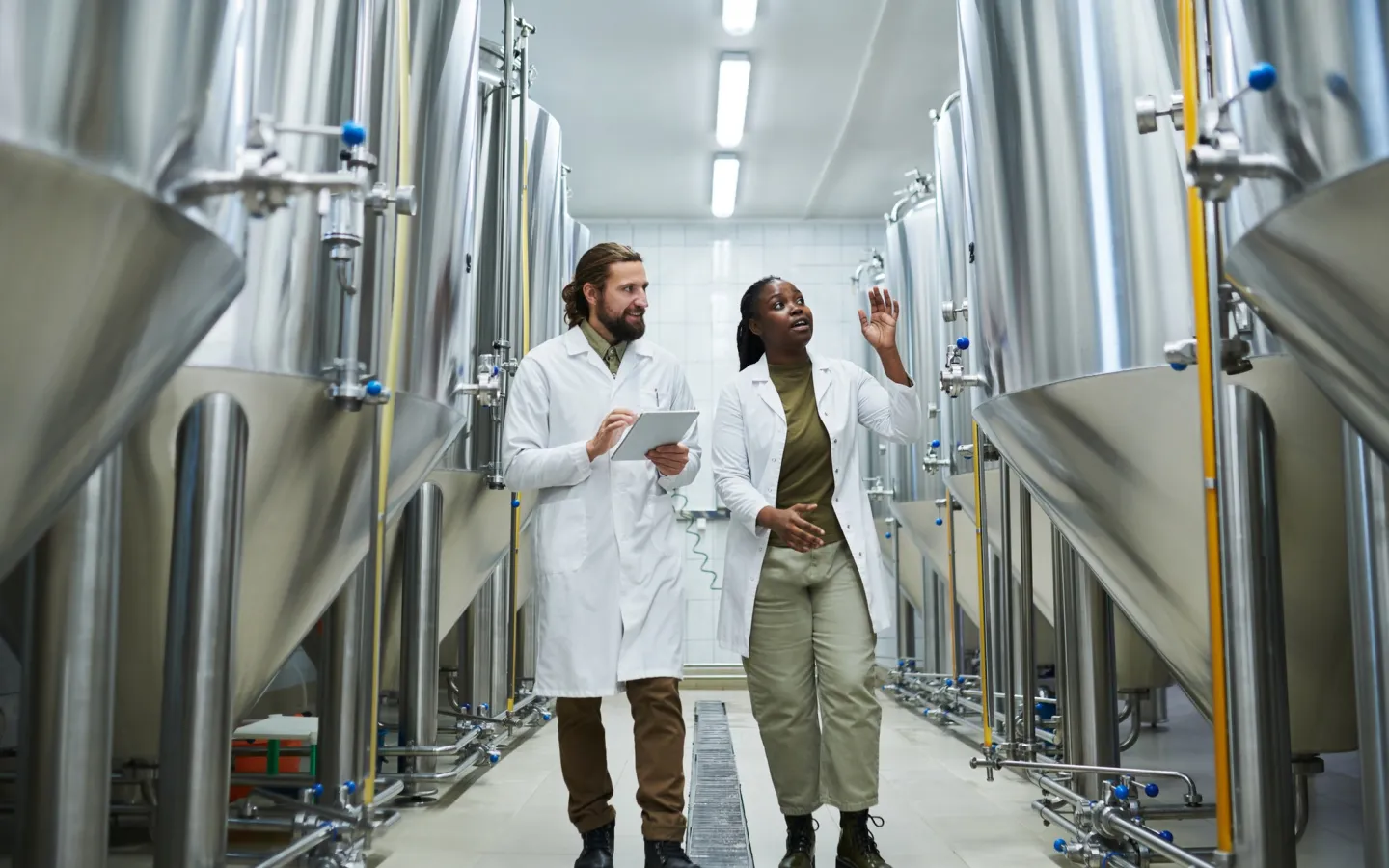 Student and professor walk together in lab with large vats