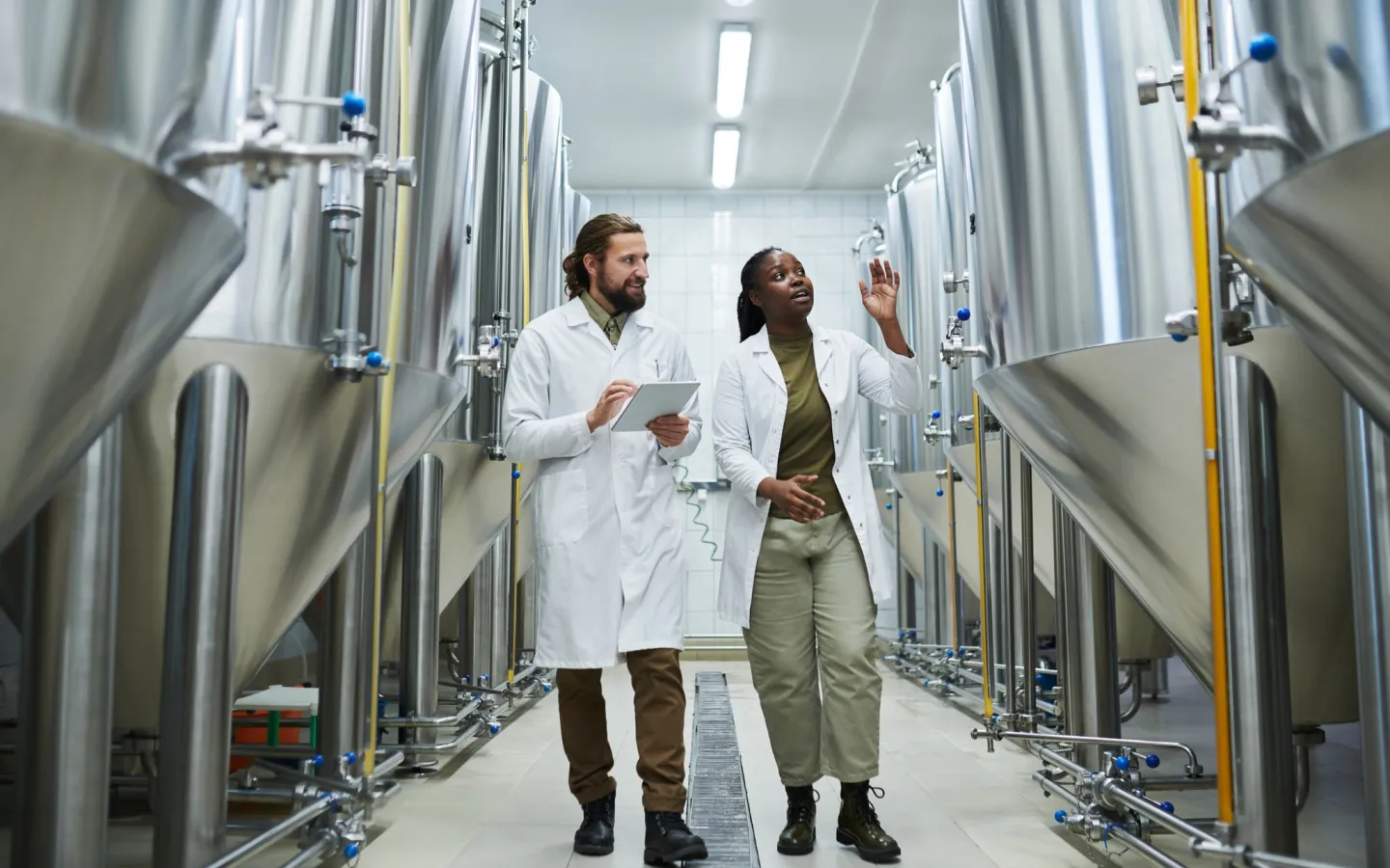 Student and professor walk together in lab with large vats