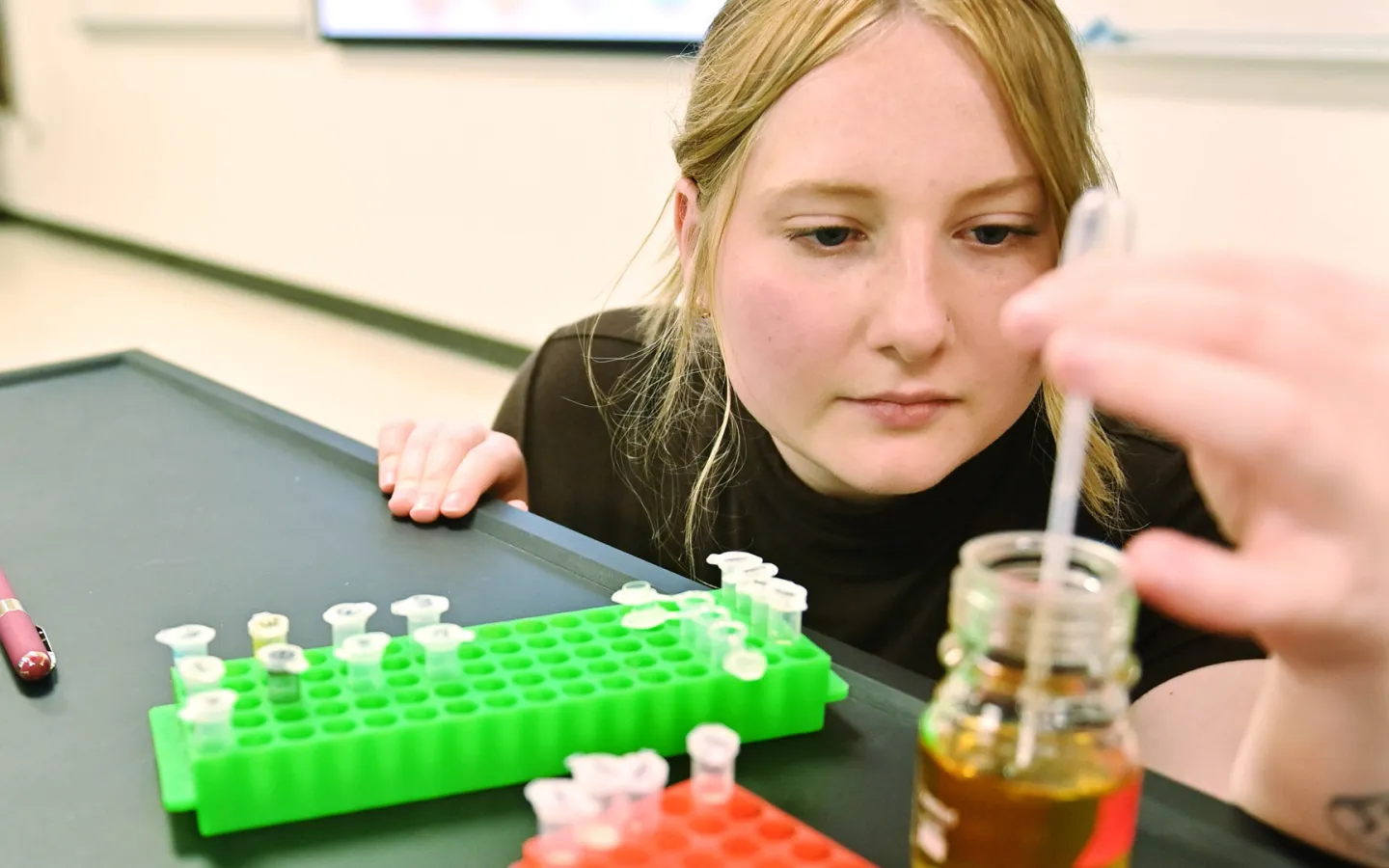 A female biology student uses the dropper tool to test a liquid