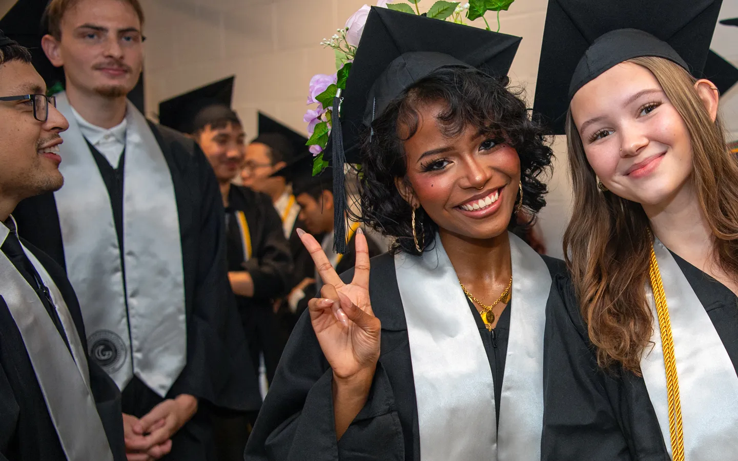 Two female graduates smile before their commencement ceremony